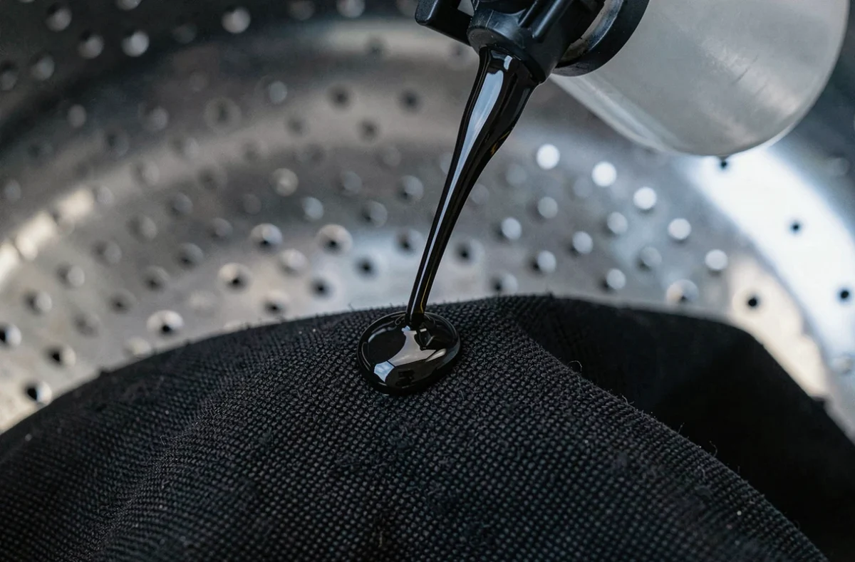 Gros plan de lessive liquide versée sur du tissu noir dans le tambour d'un lave-linge